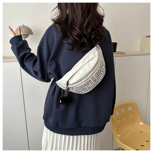 Detailansicht der weißen Harajuku Bauchtasche mit schwarzem Aufdruck und Plüsch-Anhänger