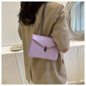 Détail du sac bandoulière matelassé lilas avec chaîne métallique et fermoir sur un modèle