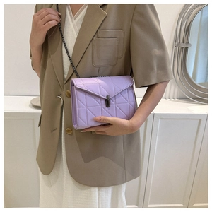 Gros plan d'un sac bandoulière matelassé lilas avec chaîne porté par un mannequin