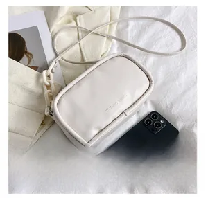 Detailed view of off-white crossbody bag with chain strap and size reference to a phone
