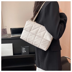 Borsa a tracolla trapuntata beige con catena dorata indossata su un blazer nero