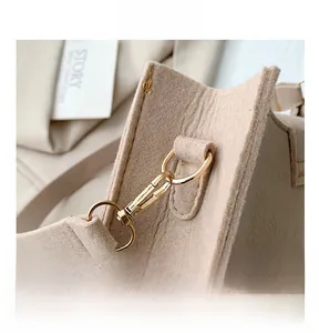 Detail of premium golden metal buckle on beige felt baguette bag for women