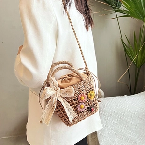 Handmade woven crossbody bag with lace bow and floral decor on a model in warm setting