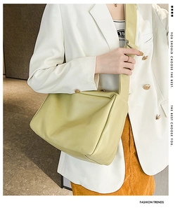 Detail of light green matte leather shoulder bag with wide strap on fashion model