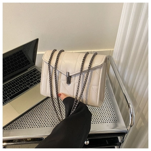Détail d'un sac matelassé blanc crème avec fermoir rotatif métallique et bandoulière