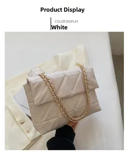 Borsa trapuntata beige con catena dorata esposta su un elegante blazer bianco puro