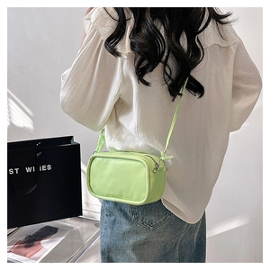 Close-up of lime green crossbody bag with double zippers and chunky chain link strap