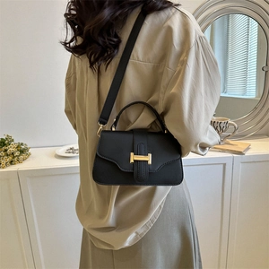 Minimalist black leather crossbody bag with a golden H-shaped clasp and top handle