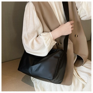 Detailed side view of soft black matte crossbody bag worn on beige outfit