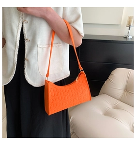 Detail of bright orange felt shoulder bag with geometric embossed texture on a model