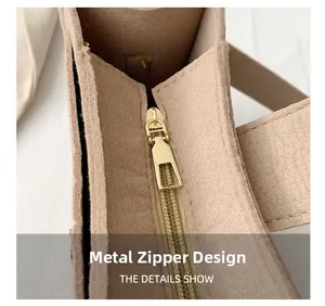 Detailed macro view of the premium golden hardware zipper on a beige felt shoulder bag