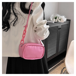 Detail of pink leather crossbody bag with chunky chain strap and fashion embossed logo