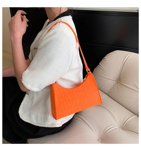 Detail view of vibrant orange underarm bag with 3D floral embossing and a slim strap
