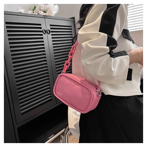 Detail of pink faux leather crossbody bag with decorative plastic chain and adjustable strap