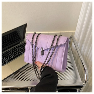 Détail du sac matelassé lavande avec bandoulière chaîne gris foncé et fermoir rotatif