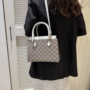 Retro monogram handbag for women featuring white leather handles and a wide shoulder strap