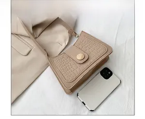 Detail of light beige crocodile pattern handbag with wood-texture buckle and phone for scale