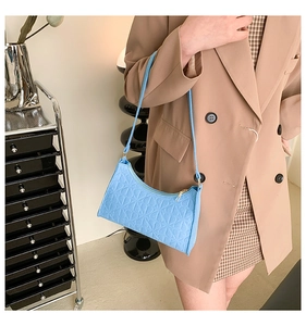 Detail of light blue underarm bag featuring geometric floral embossing and sleek strap