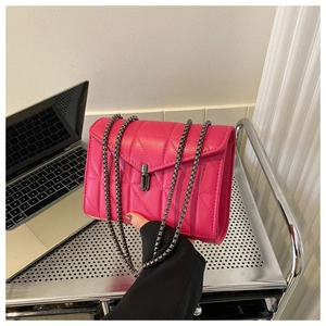 Sac bandoulière matelassé rose vif avec chaîne et fermoir sur un chariot métallique