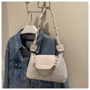 Detailed view of white floral lace texture on shoulder bag with pearl charm and chain