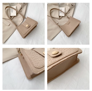 Detail of beige felt underarm bag with crocodile pattern flap and wooden button