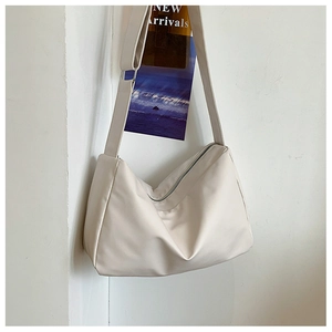 Detail view of cream white tote bag with adjustable strap and silver metal buckle