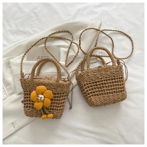 Detailed view of handmade woven straw bags with yellow flower accent and drawstring lining