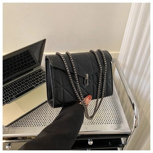 Détail du sac bandoulière en cuir matelassé noir avec chaîne en métal et fermoir carré