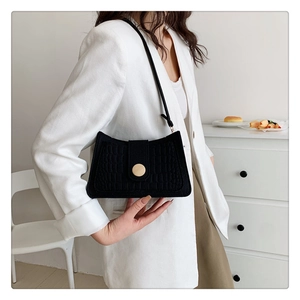 Detail of black faux crocodile leather underarm bag with decorative round wooden buckle