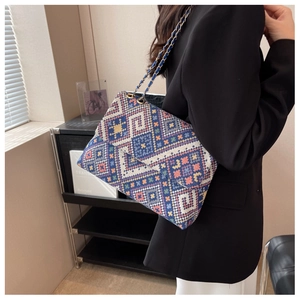 Detailed view of the colorful geometric woven pattern and golden chain strap on a crossbody bag