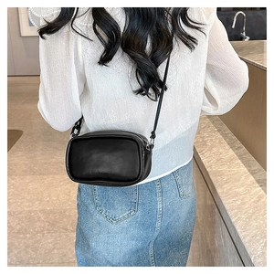 Rear view of a model wearing a black minimalist crossbody bag with fashion embossed text