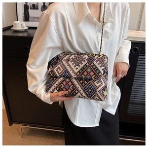 Detail of multi-color woven tote bag with geometric pattern and metal chain strap
