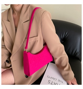 Detail of rose pink felt baguette bag with gold metal buckle shown on a model