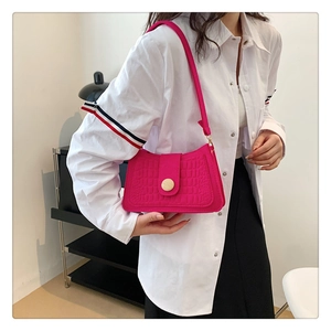 Detail of rose red crocodile embossed faux leather bag with gold circular metal buckle