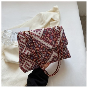 Close-up of ethnic style tote bag with red geometric jacquard and gold chain strap