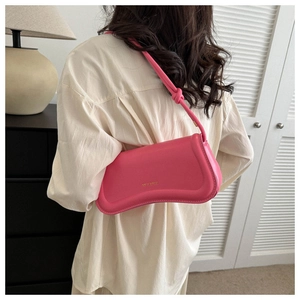 Detail of bright pink matte leather underarm bag with knot strap and gold logo