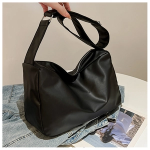 Detail of black faux leather tote bag showing soft texture and wide adjustable strap