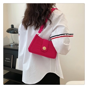 Detail of vibrant rose red crocodile pattern underarm bag with gold metal buckle