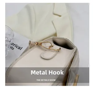 Detail of elegant gold rotating metal hook on a cream quilted crossbody bag