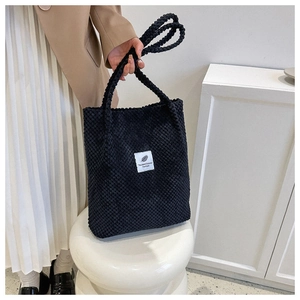Detail of black bubble texture tote bag with minimalist white woven label and feather icon