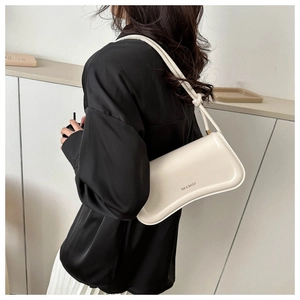 Close-up of cream white leather shoulder bag with wavy base and knotted strap detail