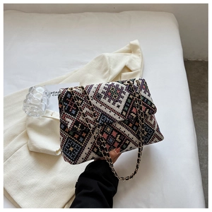 Detail of ethnic geometric woven pattern and gold chain strap on flap tote bag