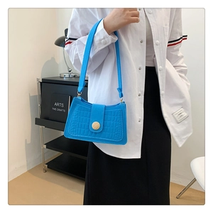 Detail of bright blue crocodile pattern underarm bag with gold metal buckle on model