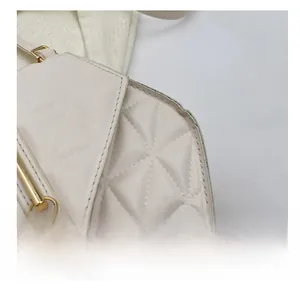 Close-up of quilted off-white handbag featuring precise triangle stitching and gold tassel