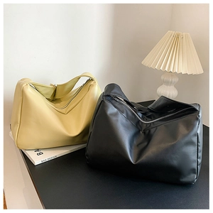 Detail of minimalist soft leather shoulder bags in yellow and black with silver zippers