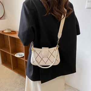 Beige quilted crossbody bag with brown trim and woven handle in a cozy home setting