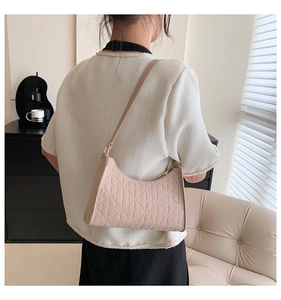 Detail of light pink shoulder bag with floral embossed pattern and gold metal zipper
