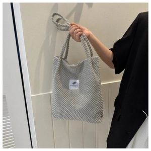 Close-up of gray corduroy tote bag showing the leaf logo label and soft fabric texture