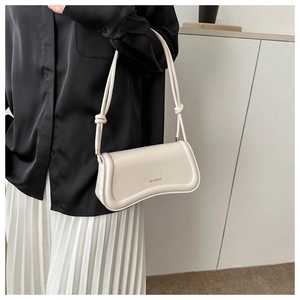 Detail of off-white underarm bag featuring knotted shoulder straps and matte leather finish