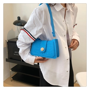 Blue crocodile pattern baguette bag with a decorative wooden button on shoulder strap